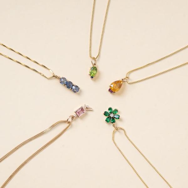 Fine gold chains with coloured gemstone pendants on cream
