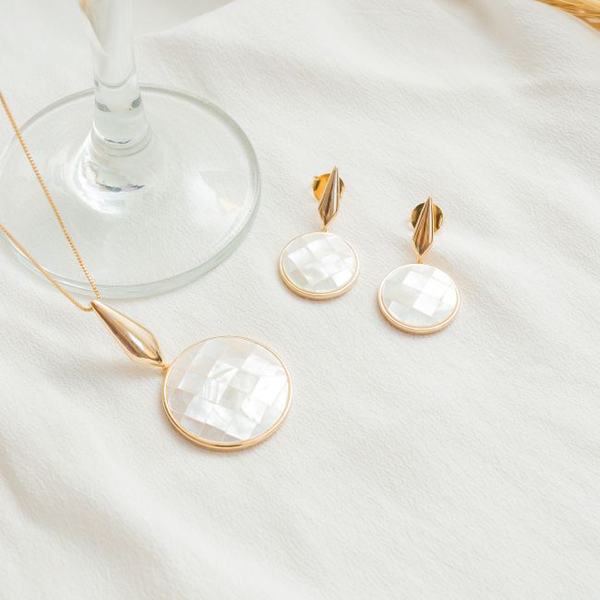 A mother-of-pearl pendant and earrings on cream linen