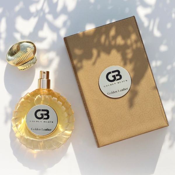 A gold fragrance bottle beside its embossed box in dappled light