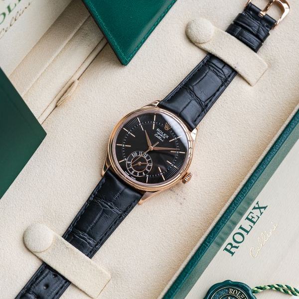 A rose gold watch on an alligator strap in its case