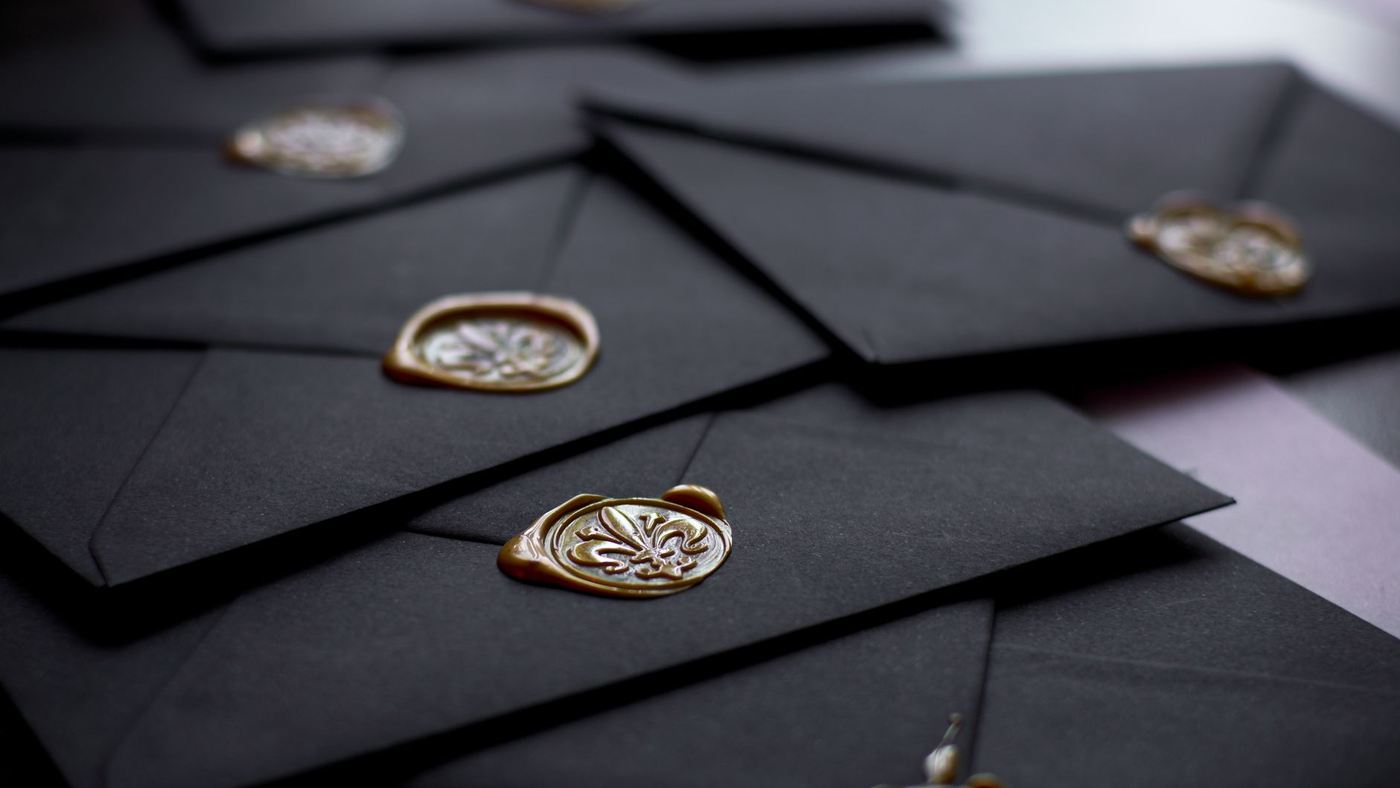 Black envelopes closed with gold wax seals