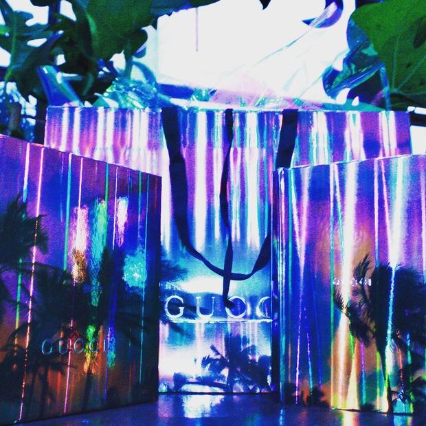 Iridescent Gucci boxes and a gift bag lit in blue and violet